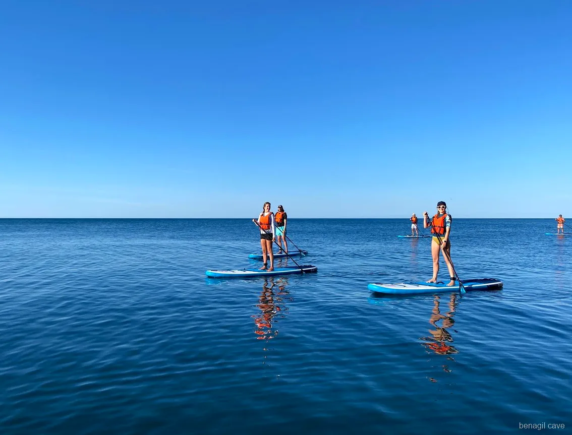 Paddleboarder near the entrance of Benagil Cave with golden cliffs behind
