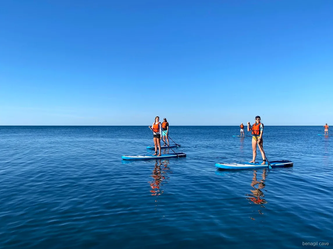 Praticante de stand up paddle perto da entrada da Gruta de Benagil com as falésias ao fundo